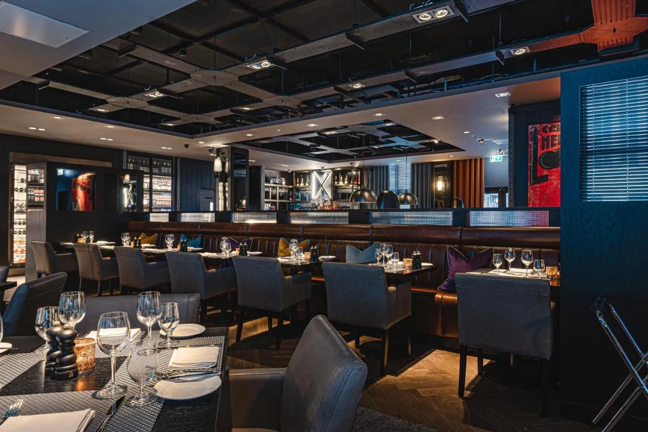 a restaurant with tables and chairs and a bar at Dakota Newcastle in Newcastle upon Tyne